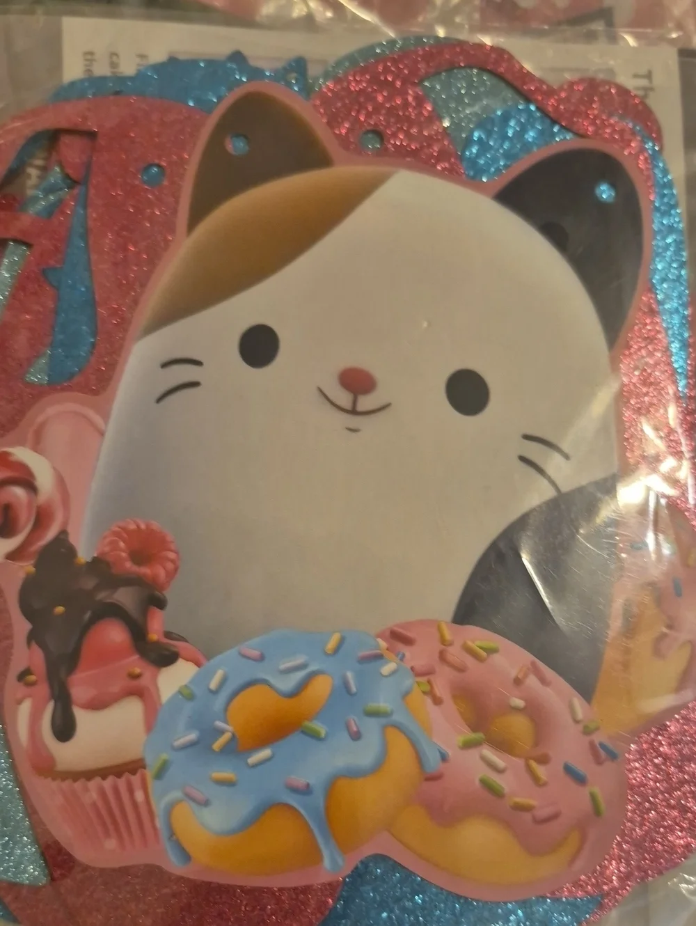 Squishmallows brand party banner featuring the character Cam the Calico Cat
